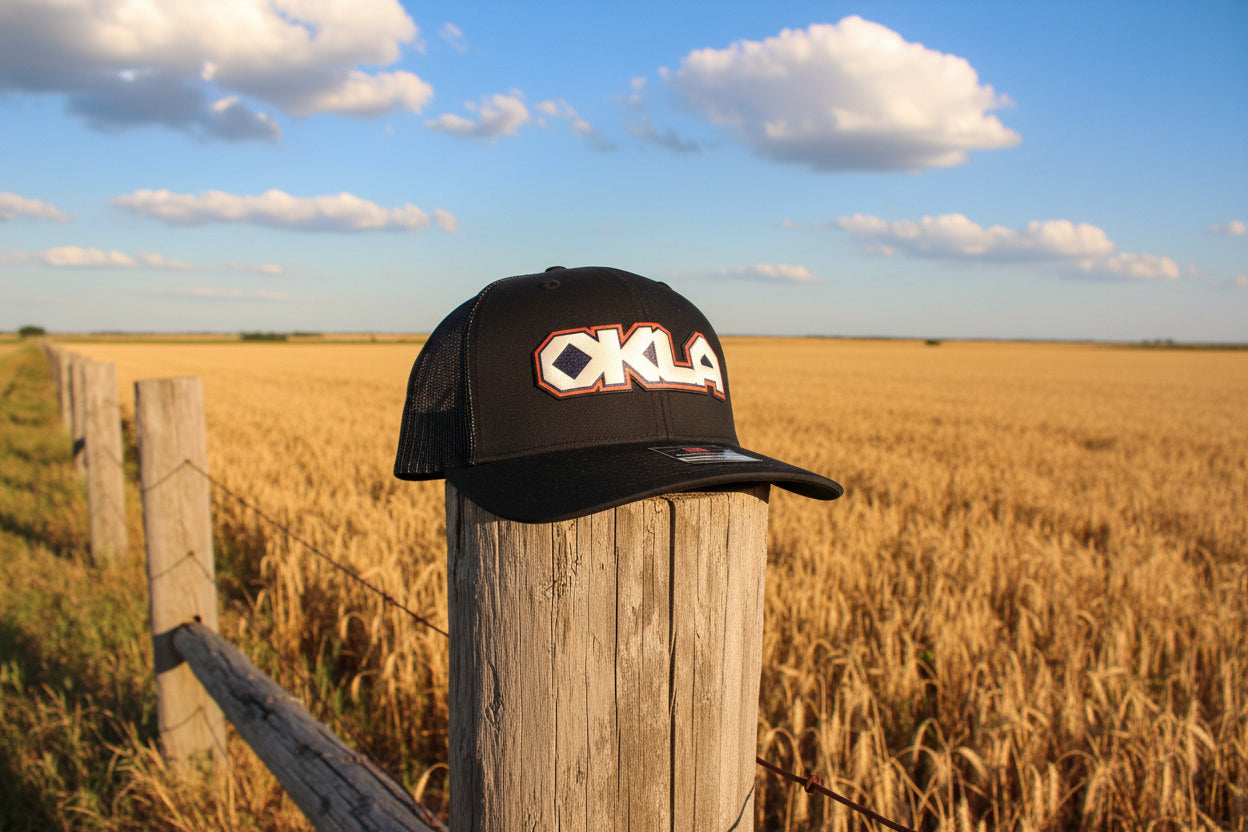 Black cap with 'OKLA' logo on a white surface
